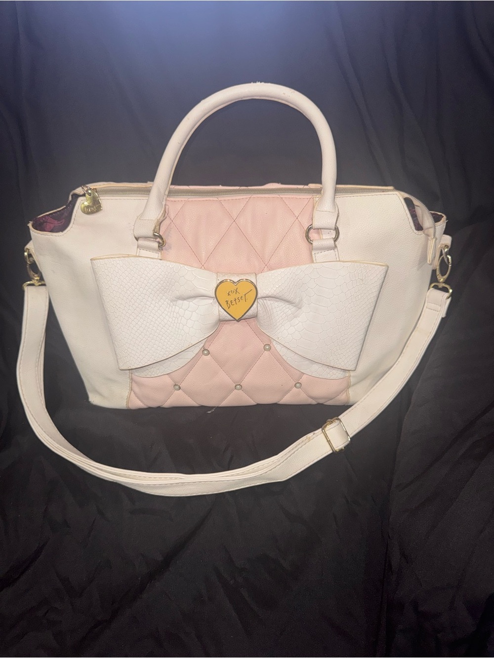 This pink and white quilted Betsey Johnson satchel features a prominent textured